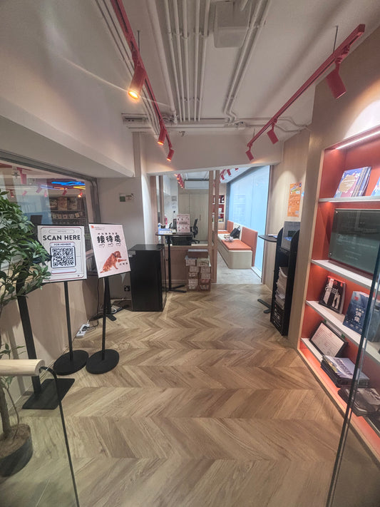 工程案例設計的香港青年聯合會馬會坪石青年空間擁有舒適的走廊,舖有木地板,配有植物、書架上的書籍,以及入口附近帶標誌的信息架。.