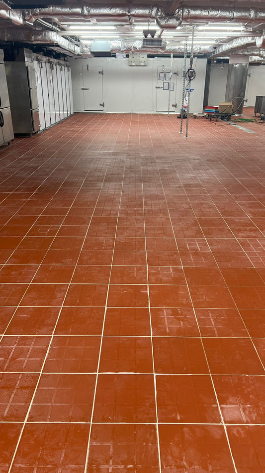 工程案例的Pie & Tart 食品工廠房間寬敞,地板鋪著紅色瓷磚,左牆邊有工業冷凍機,天花板上可以看到設備和管道。.