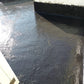 裕利工程展示觀塘大廈天台防水工程，水泥地面塗有黑色油漆。