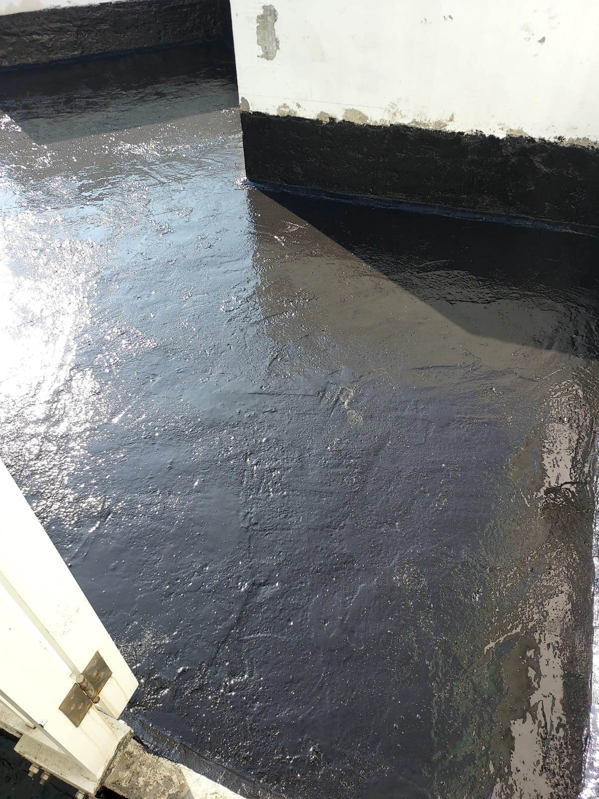 裕利工程展示觀塘大廈天台防水工程，水泥地面塗有黑色油漆。