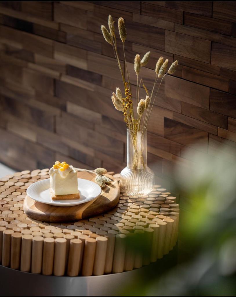 木桌上放著一盤來自工程案例九龍灣咖啡店的蛋糕。