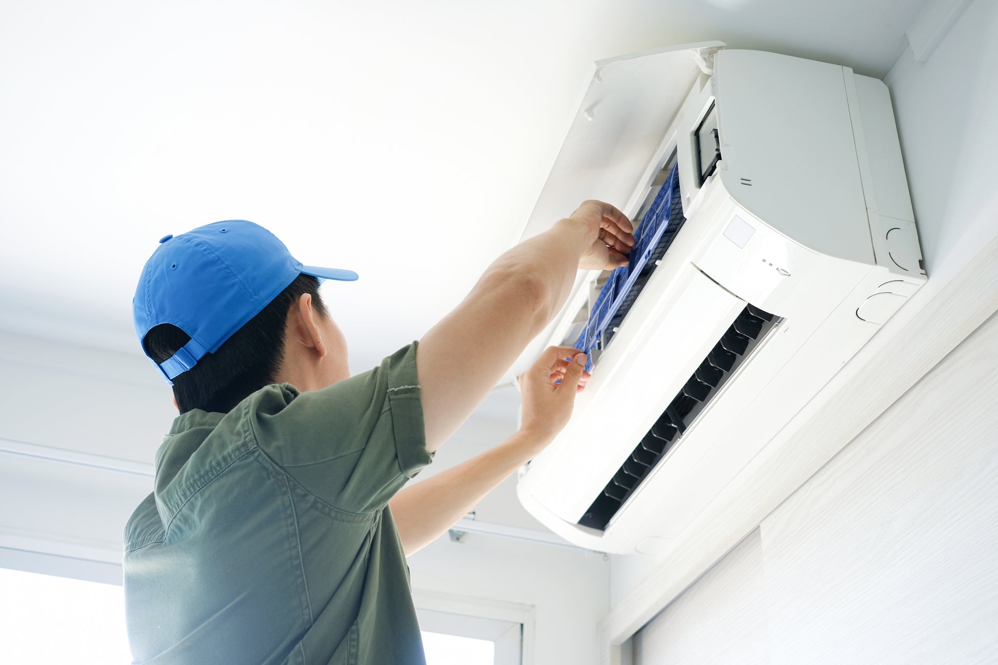 一名男子在裕利工程的房間內安裝冷氣工程空調。